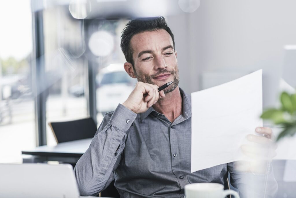 Geschäftsmann sitzt im Büro und liest einen Brief